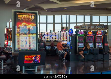 Leute, die Spielautomaten am Flughafen spielen Stockfoto