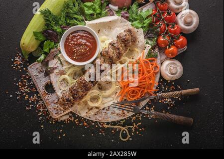 Appetitliche Hühnerschüssel. Zucchini, grüne Paprika, Tomaten, gegrillte Kartoffeln und Pilze, verschiedene Kräuter, Tomatensauce und Gewürze. Draufsicht Stockfoto