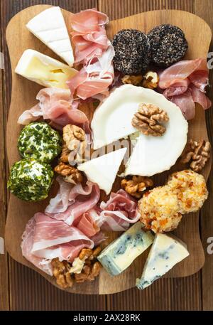 Verschiedene Käsesorten, Trauben, Walnüsse, Honig und Prosciutto. Holzschneidplatte. Stockfoto