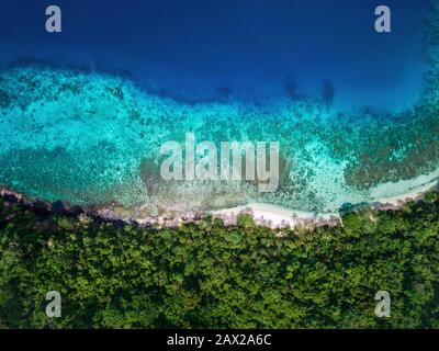 Tropisches Inselstrandparadies, Luftblick oben unten auf türkisfarbenes Wasser und üppige Vegetation am abgeschiedenen weißen Strand. Stockfoto