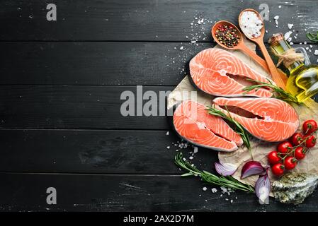 Rohes Lachssteak mit Zutaten auf schwarzem Hintergrund. Draufsicht. Freier Speicherplatz für Ihren Text. Stockfoto