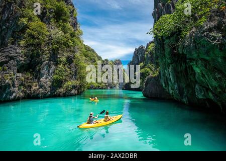 Touristen auf Kajaks, die an einem sonnigen Tag auf der Insel Palawan auf den Philippinen die natürlichen Sehenswürdigkeiten rund um El Nido erkunden. Stockfoto