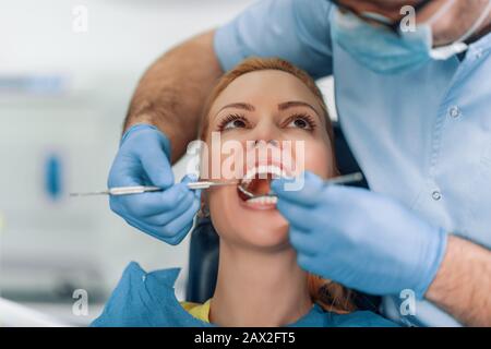 Schöne weibliche Patientin, die zahnärztliche Behandlung im Zahnarztbüro hat.Dentist und eine Patientin.People,Medizin,Stomatologie und Gesundheitskonzept. Stockfoto