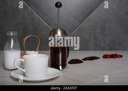 Niedriger Blickwinkel auf Kaffeebeeren, Bohnen und Boden auf der Theke mit Kaffeebrühen für die französische Presse. Stockfoto