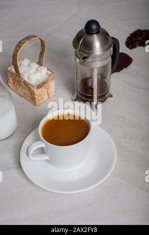 Hoher Winkel, vertikaler Blick auf Kaffeebeeren, Bohnen und Böden, die auf der Theke mit frisch gebrühtem französischen Presskaffee gezeigt werden. Stockfoto