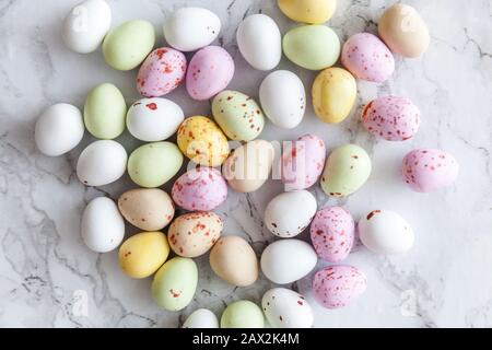 Frohe Ostern Konzept. Vorbereitung für den Urlaub. Ostern Eier in Pastellfarben Süßigkeiten Schokolade Bonbons auf trendige grauem Marmor Hintergrund. Einfache Minimalismus flach Ansicht von oben kopieren Raum Stockfoto