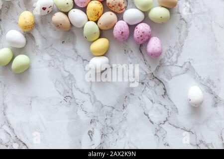 Frohe Ostern Konzept. Vorbereitung für den Urlaub. Ostern Eier in Pastellfarben Süßigkeiten Schokolade Bonbons auf trendige grauem Marmor Hintergrund. Einfache Minimalismus flach Ansicht von oben kopieren Raum Stockfoto
