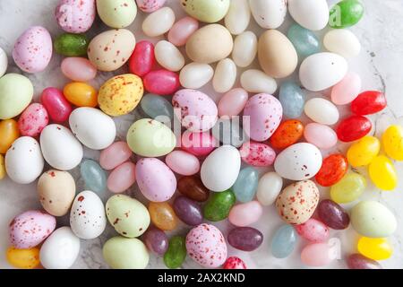 Frohe Ostern Konzept. Vorbereitung für den Urlaub. Ostern Süßigkeiten Schokolade Eier und fruchtgummi Bonbons auf trendige grauem Marmor Hintergrund. Einfache Minimalismus flach Ansicht von oben kopieren Raum Stockfoto