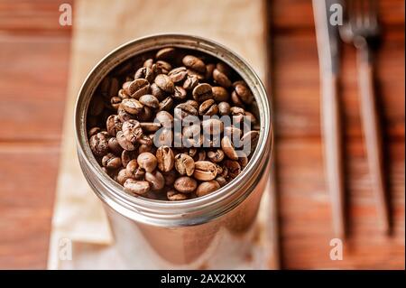 Kaffeebohnen in einer Dose. Gerösteter aromatischer Kaffee aus nächster Nähe. Sonnenlicht auf dem Hintergrund Stockfoto