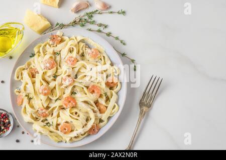 Pasta mit Garnelen, cremiger Soße, Parmesankäse und Thymian auf einem Teller. Mediterrane Tagliatelle mit Meeresfrüchten. Italienische Küche. Draufsicht Stockfoto