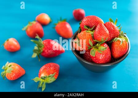 Blaues Tuch mit einer Schüssel frischer Erdbeeren auf einem Holztisch Stockfoto