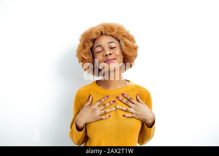 Die ehrliche afroamerikanische Frau hält die Hände auf der Brust, die ihre herzliche Dankesbekundung zeigt, drückt Freundlichkeit aus. Sprache des Körpers. Stockfoto