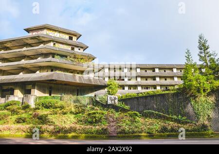 Sete Cidades, Azoren, Portugal - 12. Januar 2020: Verlassenes Hotelgebäude auf dem berühmten Aussichtspunkt auf den portugiesischen Inseln. Leerbetonbau von außen. Grüne Bäume um. Stockfoto