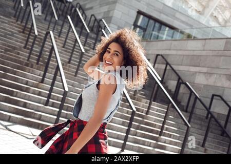 Junge Frau in der Stadtstraße lächelnd fröhlich auf einer Treppe stehend Stockfoto