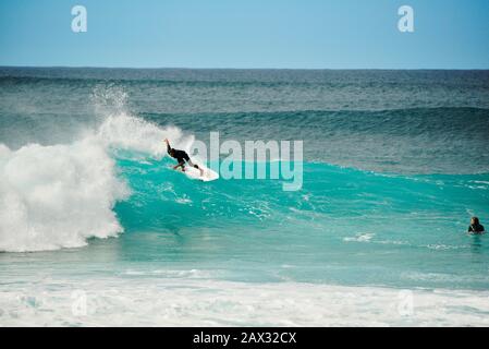 Männliche Surfer, die in Der Banzai-Pipeline an Nordufer, Oahu Island, Haleiwa, Hawaii, USA, mit weltweit bekannten, krachenden, geschwungenen türkisfarbenen Wellen reiten Stockfoto