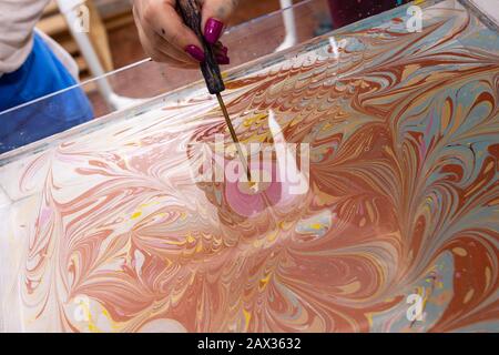 Meisterklasse im Atelier Ebru - die Kunst des "Malens auf dem Wasser." Frauenhände schließen sich. Stockfoto
