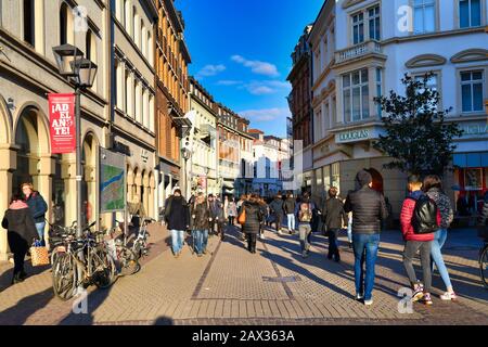Heidelberg, Februar 2020: Menschen, die am kalten sonnigen Wintertag die historische Einkaufsstraße in der Innenstadt hinunter gehen Stockfoto