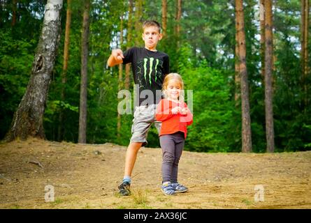 Ein Junge und ein Mädchen tanzen fröhlich in einer Lichtung im Wald Stockfoto