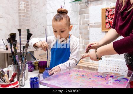 Die Lehrerin zeigt die Techniken des Mädchens, um Gemälde zu erstellen. Meisterklasse im Atelier Ebru - die Kunst des "Malens auf dem Wasser". Stockfoto