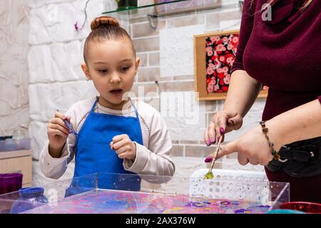 Die Lehrerin zeigt die Techniken des Mädchens, um Gemälde zu erstellen. Meisterklasse im Atelier Ebru - die Kunst des "Malens auf dem Wasser". Stockfoto