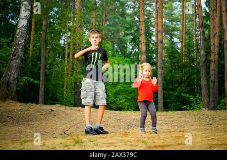 Ein Junge und ein Mädchen tanzen fröhlich in einer Lichtung im Wald Stockfoto