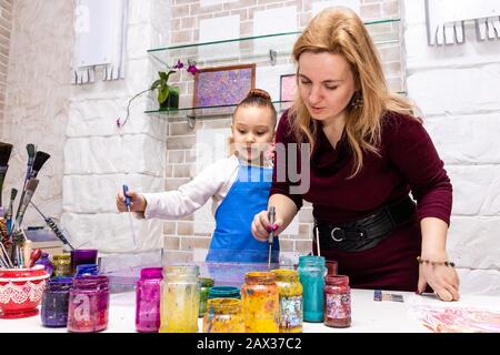 Die Lehrerin zeigt die Techniken des Mädchens, um Gemälde zu erstellen. Meisterklasse im Atelier Ebru - die Kunst des "Malens auf dem Wasser". Stockfoto