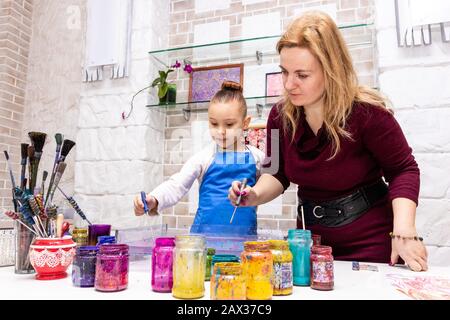 Die Lehrerin zeigt die Techniken des Mädchens, um Gemälde zu erstellen. Meisterklasse im Atelier Ebru - die Kunst des "Malens auf dem Wasser". Stockfoto