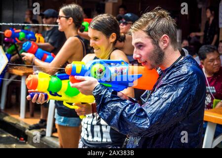 Kaukasische Touristen schießen Wasserpistolen auf dem Songkran Festival, dem traditionellen thailändischen Neujahr, an der Khao San Road in Bangkok, Thailand. Stockfoto