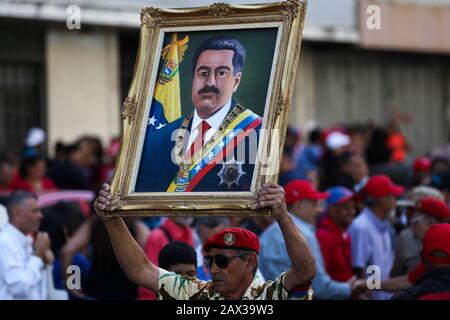 10. Februar 2020, Venezuela, Caracas: Ein Anhänger der Regierung hebt ein Porträt des venezolanischen Staatschef Maduro auf, in dem Protest gegen die Ankündigung neuer Sanktionen gegen die venezolanische Fluggesellschaft Conviasa durch die USA. "Die staatliche Fluggesellschaft Conviasa unterstützt das illegale Regime Maduros durch Flüge von Beamten seines korrupten Regimes auf der ganzen Welt", zitierte das US-Finanzministerium Finanzminister Mnukhin bei der Ankündigung neuer Sanktionen. "Wir werden an internationale Gerichte appellieren", konterte der venezolanische Staatschef Maduro während des Protests vor zahlreichen Anhängern Stockfoto