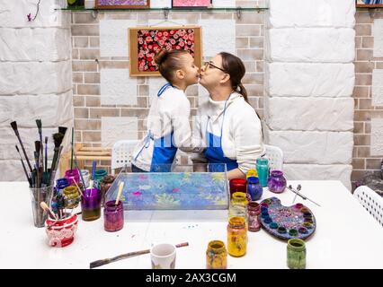 Meisterklasse im Atelier Ebru - die Kunst des "Malens auf dem Wasser." Mama küsst Tochter 6 Jahre nach Abschluss einer Kunststunde. Stockfoto