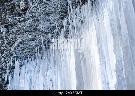 Blick unter einem gefrorenen Wasserfall, Eisvorhang aus Eiszapfen Stockfoto