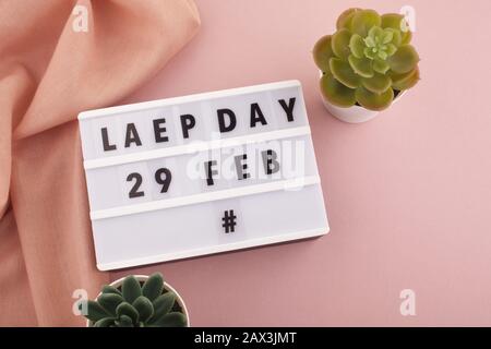 Der weiße Blockkalender ist am 29. Februar und am Monat Februar zu sehen und wird auf pinkfarbenem Hintergrund gehalten. Schalttag Stockfoto
