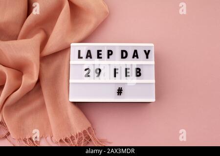 Weißer Blockkalender, das Datum 29. Februar und der Monat Februar sowie der Schal auf pinkfarbenem Hintergrund. Schalttag Stockfoto