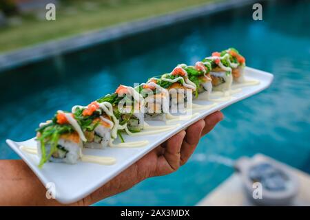 Halten Sie ein Tablett mit Sushi vor dem Pool Stockfoto