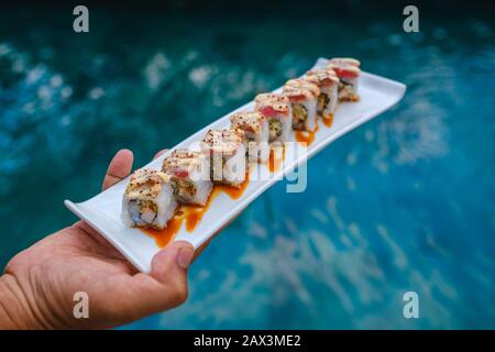 Halten Sie ein Tablett mit Sushi vor dem Pool Stockfoto