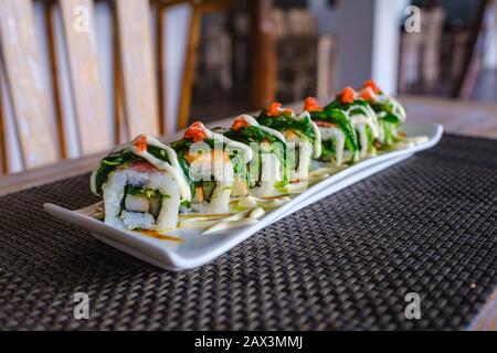 Weißes Tablett von verschiedenen Arten von Sushi auf einem Dunkle Oberfläche Stockfoto