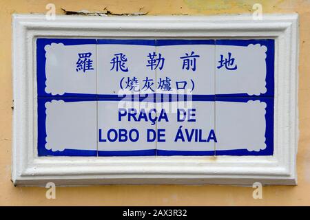 Ein Straßenschild in Macau auf Chinesisch und Portugiesisch Die Praca de Lobo de Avila an einer Wand Stockfoto