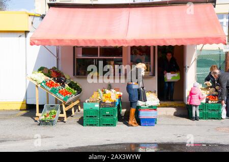 Posen, POLEN - 26. März 2014: Frau kauft frische Lebensmittel vor einem kleinen Geschäft, in dem Gemüse und Obst verkauft werden. Stockfoto