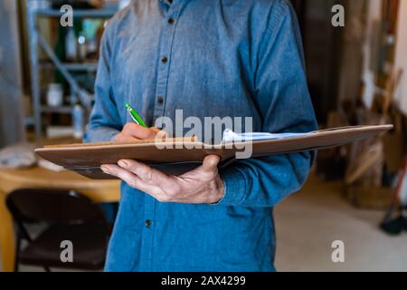 Nahaufnahme und selektive Fokussierung eines Notebooks mit einem Lederbezug, der vom Inspektor während der professionellen Notizen gehalten wird. Bei einer Hauskontrolle Stockfoto