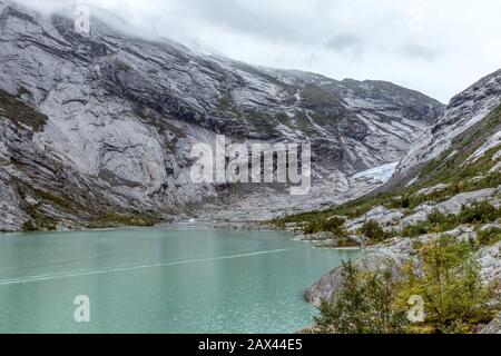 Norwegen Berge Landschaft Blick in der Nähe des Sees mit azurblauem Wasser, Felsen, Gletscher, Schnee. Bewölkte Tages-Tracking-Reise nach Nigardsbreen in Jostedalsbreen Nati Stockfoto