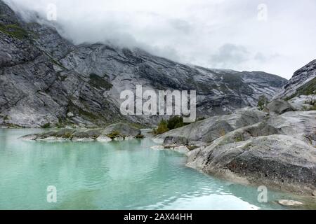 Norwegen Berge Landschaft Blick in der Nähe des Sees mit azurblauem Wasser, Felsen, Gletscher, Schnee. Bewölkte Tages-Tracking-Reise nach Nigardsbreen in Jostedalsbreen Nati Stockfoto