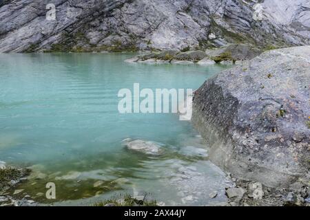 Norwegen Berge Landschaft Blick in der Nähe des Sees mit azurblauem Wasser, Felsen, Gletscher, Schnee. Bewölkte Tages-Tracking-Reise nach Nigardsbreen in Jostedalsbreen Nati Stockfoto