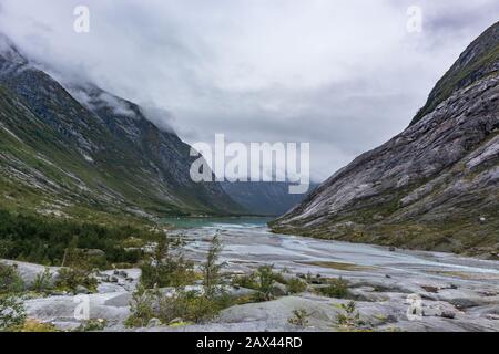 Blick auf die Landschaft des norwegischen Gebirges mit azurblauem Wasser und Felsen. Bewölkte Tagesausfahrt nach Nigardsbreen im Jostedalsbreen-Nationalpark Stockfoto