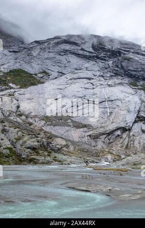 Berge Norwegens Felsen vertikale Wandlandschaft mit azurblauem Wasser. Bewölkte Tagesausfahrt nach Nigardsbreen im Jostedalsbreen-Nationalpark Stockfoto