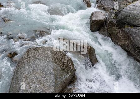 Berge Blau sprudelnder Kaltwasserfluss, der auf grauen Felsen aus Granit abfließt, Naturausflug in die nördlichen wilden Hochgebirge Stockfoto