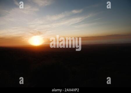 Dunkle Natur bei Sonnenuntergang mit Meereswellen und Bergen im Hintergrund Stockfoto