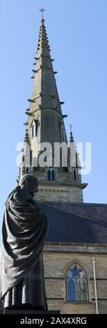 Kardinal-Patrick O'Donnell-Statue vor dem viktorianischen neugotischen Turmspitze und der Kathedrale von St Eunan in Letterkenny, County Donegal, Irland. Stockfoto