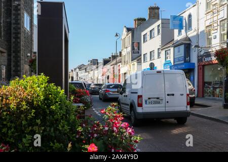 Ein weißer Lieferwagen, der an einem sonnigen Herbstmorgen in einer engen Einbahnstraße mit blauem Himmel im Letterkenny County Donegal, Irland, in einer Verkehrslinie geparkt wurde. Stockfoto