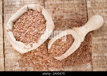 Leinsamen im Behälter und Löffel auf dem Tisch. Stockfoto