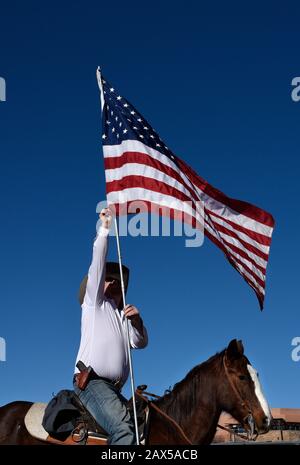 Ein Mitglied einer Gruppe namens Cowboys for Trump, das mit einer Waffe bewaffnet auf einem Pferd reitet und eine amerikanische Flagge trägt, nimmt an einer Pro-Trump-Kundgebung Teil. Stockfoto